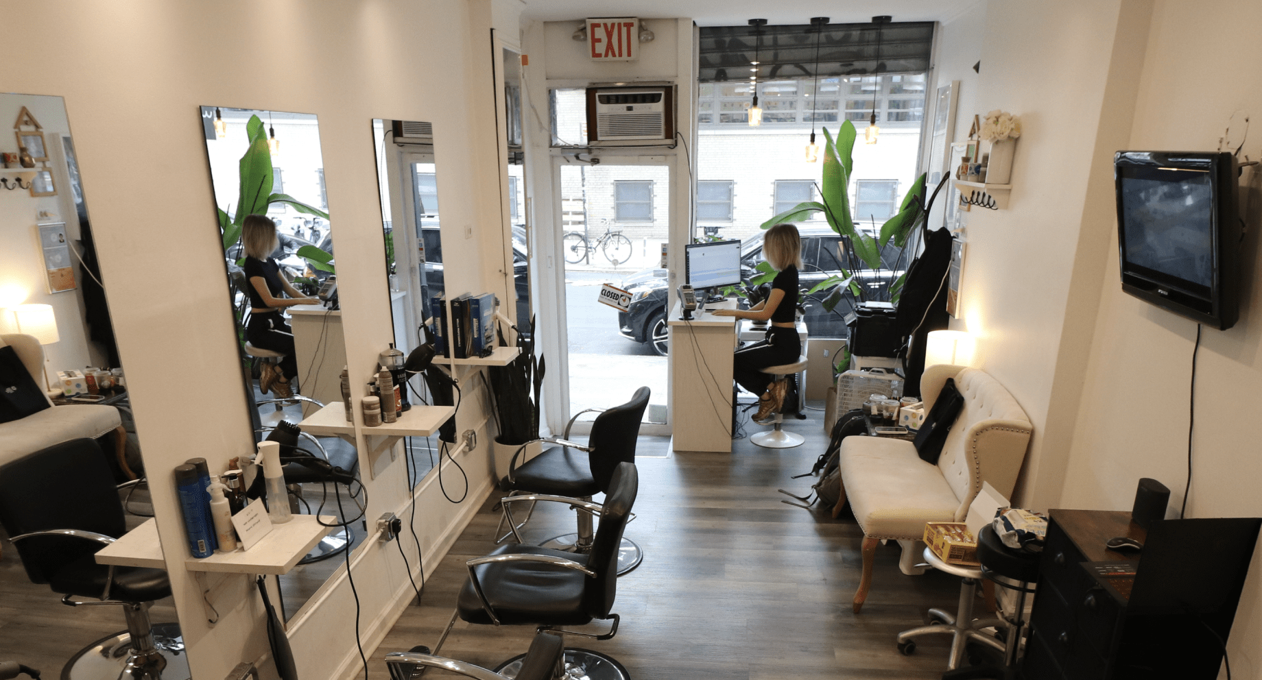 The interior of Wind Hair Salon, with big mirrors, black chairs, three seats, and hairstyling equipments